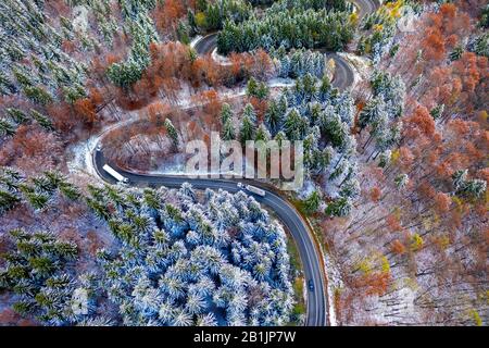 Luftbild einer kurvenreichen Bergstraße, die durch einen Tannenwald führt. Winter mit Schnee Stockfoto