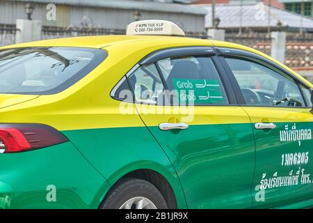 Ein Bangkok Grab Taxi-Servicewagen, in traditioneller grüner und gelber Farbgebung. Stockfoto