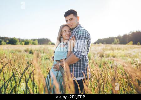 Der Kerl küsst die Stirn des Mädchens in einem Weizenfeld Stockfoto