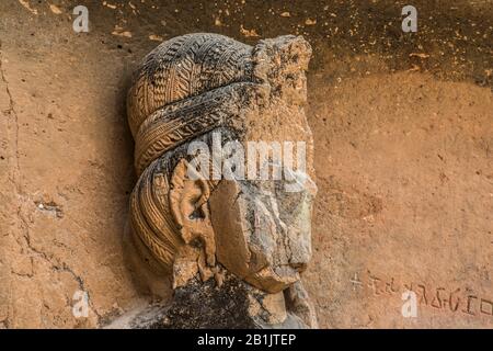 Kondana-Höhlen, Karjat, Maharashtra, Indien: EINE Yaksha-Figur mit aufwendiger Kopfbedeckung, links von der façade der Chaitya-Halle. Stockfoto