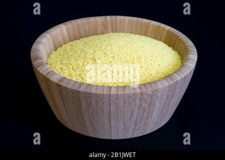 Trockenes Couscous Nahaufnahme in einer tiefen Schale aus Bambus auf dunklem Hintergrund. Konzept der orientalischen Küche. Stockfoto