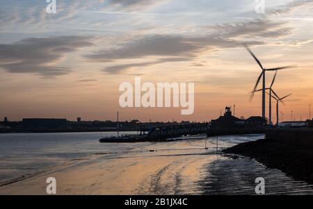 Abenddämmerung im Hafen von Tilbury, Essex, Großbritannien. Blick auf den Sonnenuntergang über der Themse und Windturbinen im Hintergrund. Stockfoto