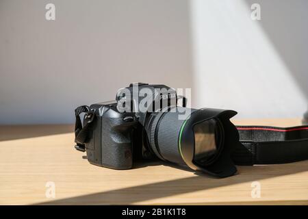 Wasserdichtes DSLR Pentax K3 Kameragehäuse mit 18-135 mm Objektivsatz auf Holztisch unter Sonneneinstrahlung Stockfoto