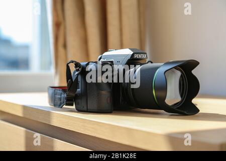 Wasserdichtes DSLR Pentax K3 Kameragehäuse mit 18-135 mm Objektivsatz auf Holztisch unter Sonneneinstrahlung Stockfoto