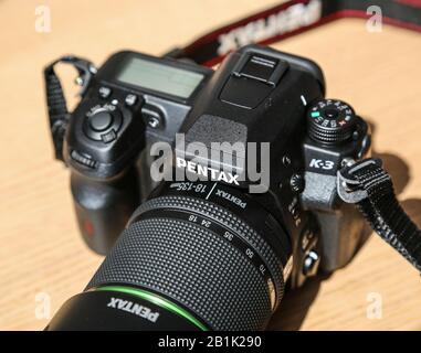 Wasserdichtes DSLR Pentax K3 Kameragehäuse mit 18-135 mm Objektivsatz auf Holztisch unter Sonneneinstrahlung Stockfoto