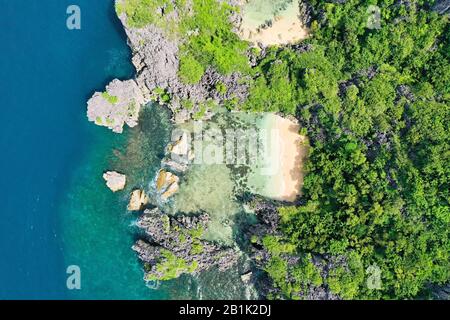 Matukad Island, Karamoische Inseln, Philippinen. Wilder weißer Sandstrand. Sommer- und Reiseurlaubskonzept. Felseninsel mit weißem Sandstrand, Blick von oben. Luftaufnahme von oben auf Wellen, Strand und felsige Küste und wunderschönen Wald. Stockfoto