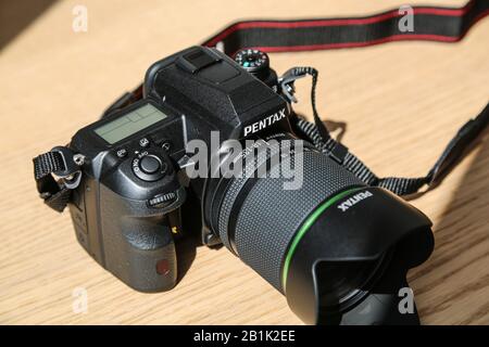 Wasserdichtes DSLR Pentax K3 Kameragehäuse mit 18-135 mm Objektivsatz auf Holztisch unter Sonneneinstrahlung Stockfoto