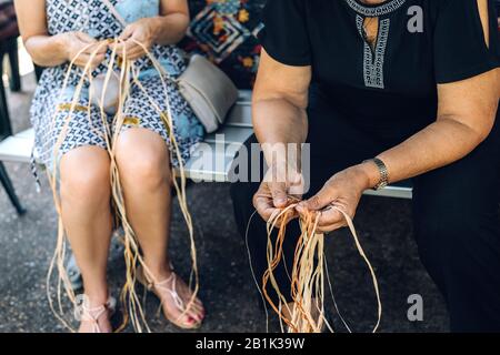 Zwei Weibchen weben Körbe auf der Handwerkerwerkstatt. Hände, die das Handwerk halten, Nahaufnahme. Stockfoto