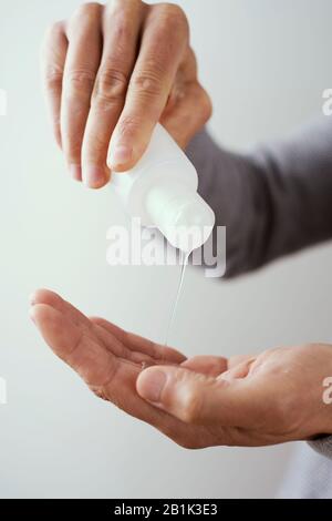 Nahaufnahme eines kaukasischen Mannes, der seine Hände mit Händededesinfektionsmittel aus einer Flasche desinfiziert Stockfoto