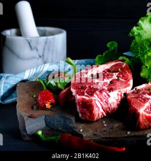 Fleischkonzept. Fleischsteaks können mit auf dem Tisch liegendem Gemüse zubereitet werden Stockfoto