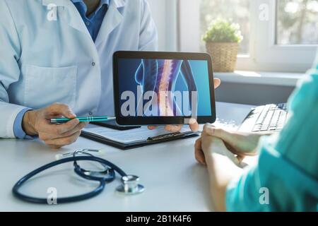 Arzt und Patient sprechen über Rückenschmerzen in der Klinik Stockfoto