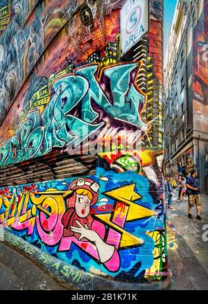 Cartoon-Gemälde auf einer stark graffit vermauerten Gasse mit Kopfsteinpflaster, mit Menschen im Hintergrund, Hosier Street, Melbourne Lanes, Melbourne, Vic Stockfoto