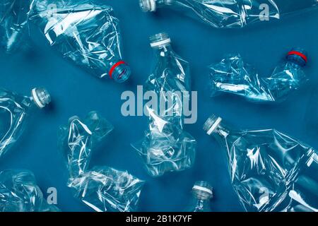 Viele gebrauchte Plastikflaschen auf blauem Hintergrund. Das Konzept der Verschmutzung des Planeten und der Ozeane durch Plastikmüll. Stockfoto
