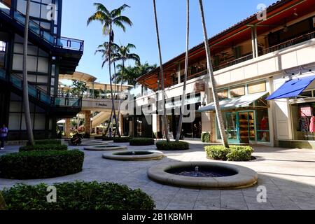Ein paar Leute in einem gepflasterten Innenhof der Geschäfte im Merrick Park, einem gehobenen Einkaufszentrum im Freien in Coral Gables, Miami, Florida, USA. Stockfoto