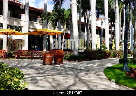 Der strahlend gelbe Sonnenbrellas mit Sonnendach fügt das Ambiente des Restaurants im Freien in den Geschäften von Merrick Park, dem gehobenen Einkaufszentrum Coral Gables, Miami, FL, USA hinzu. Stockfoto