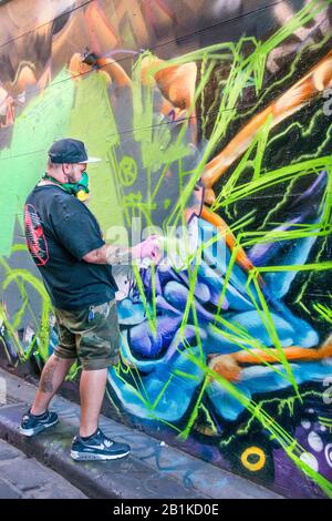 Junger Mann mit Maskenspray, das Graffiti in der Hintergasse, Hosier Street, Melbourne Lanes, Melbourne, Victoria, Australien malt Stockfoto