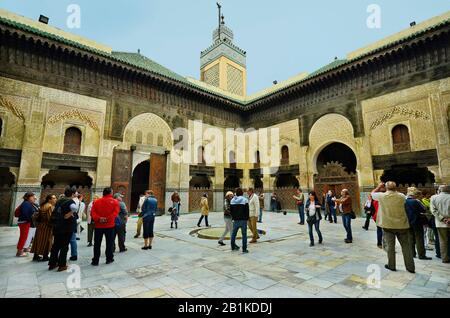 Fez, Marokko - 20. November 2014: Nicht identifizierte Touristen im Innenhof von Medersa Bou Inania mit kunstvollen Verzierungen - eine islamschule - madr Stockfoto