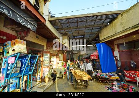 Fes, Marokko - 20. November 2014: Unidentifizierte Menschen und Straßenhändler mit Radtraufe in Souk fes el-Bali, traditionelles Einkaufszentrum Stockfoto
