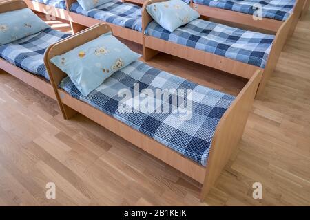 Viele kleine Betten mit frischer Bettwäsche in der Kindertagesstätte Vorschule leere Schlafzimmer Innenraum für komfortable Mittagsschlaf der Kinder. Stockfoto