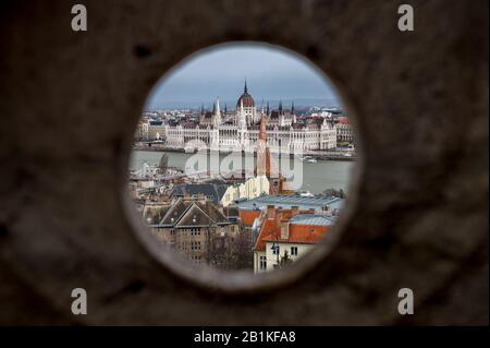Das ungarische Parlamentsgebäude, das durch ein Loch in der Fischerbastion auf dem Buda-Hügel, Budapest mit, gesehen wird Stockfoto