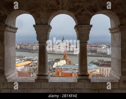 Das ungarische Parlamentsgebäude, das durch die Arkaden der Fischerbastei auf dem Buda-Hügel, Budapest mit, gesehen wird Stockfoto