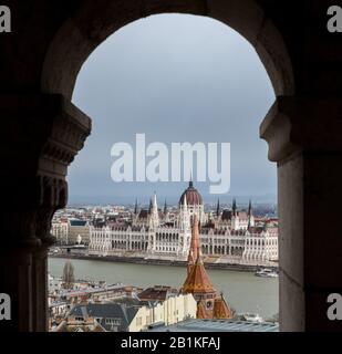 Das ungarische Parlamentsgebäude, das durch eine Arkade der Fischerbastei auf dem Buda-Hügel, Budapest mit, gesehen wird Stockfoto