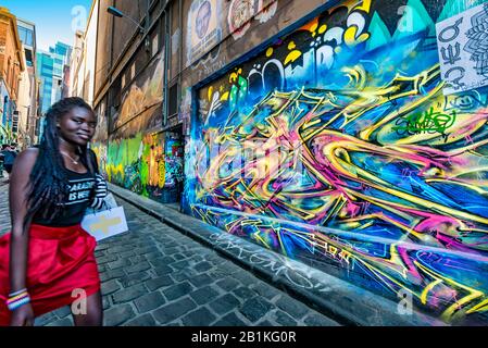 Junge, modische schwarze Frau mit rotem Minirock, schwarzem Geflechte, Spaziergang auf gepflasterter Straße, Hosier Street, Melbourne Lanes, Melbourne, Victoria, Stockfoto