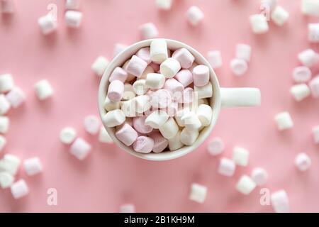 Pinkfarbene und weiße Mini-Marshmallows in Tasse mit heißer Schokolade auf pinkfarbenem Hintergrund Stockfoto