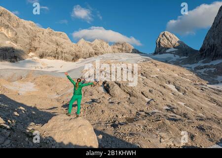 Wanderer streckt Arme in der Luft, Alpenlandschaft, Großer Gosaugletscher, hohes Kreuz, hoher und Niederer Dachstein, Salzkammergut, Oberösterreich Stockfoto