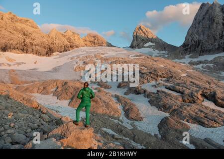 Sonnenuntergang, Wanderer blickt auf alpine Landschaft, Großen Gosaugletscher, hohes Kreuz, hoher und Niederer Dachstein, Mitterspitz, Salzkammergut, Oberösterreich Stockfoto