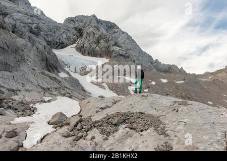 Wanderer blickt auf alpine Landschaft, Schneelochgletscher, Niederes Kreuz, Dachstein, Salzkammergut, Oberösterreich, Österreich Stockfoto