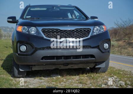 SUV mit Menschen in den Bergen. Auto in den Bergen. Rennkonzept. SUV mit Schlamm bedeckt. Crossover überwindet am Herbsttag im Wald Hindernisse. Aus Stockfoto