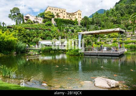 Meran, Südtirol, Italien - 4. Juli 2016. Blick auf den botanischen Garten und das Schloss Trauttmansdorff-Schloss, über den Teich, in Meran, Italien. Blick mit Menschen Stockfoto