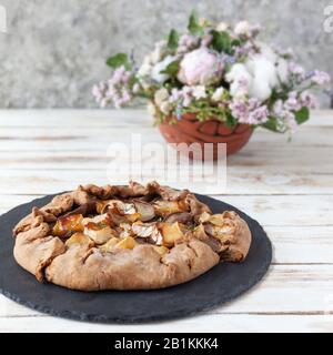 Galette mit Birnen und Käsebrie. Auch bretonische Galette genannt, Galette des Rois, Galeta. Französische Küche. Auf altem weißen Holzhintergrund. Stockfoto