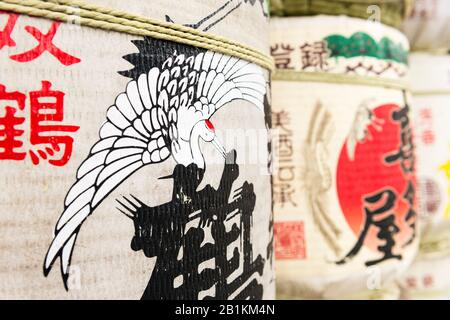 Sake-Fässer, die in der japanischen Kunst, einschließlich eines Flugstorchs, in Kushida-jinja, einem Shinto-Schrein, bedeckt sind. Hakata-ku Altstadt, Fukuoka Stockfoto