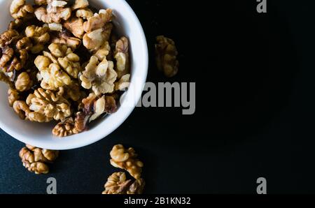 Superfood, Walnüsse in einer weißen Platte auf schwarzem Hintergrund Draufsicht Stockfoto