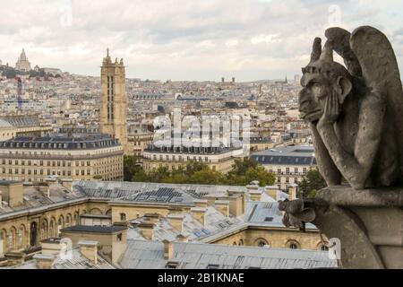 Blick von einem der Türme von Notre-Dame mit typisch französischer Architektur Und Sacre Coure in der Ferne mit einem Gargoyle in Der Vordergrund Stockfoto