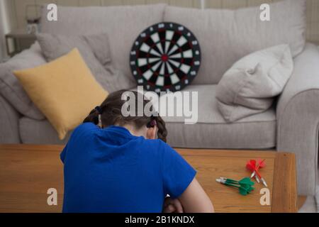 Ein junges Mädchen, das zuhause Darts spielt Stockfoto