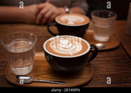 Zwei Mocha-Kaffees mit Wasser werden in einem Café serviert Stockfoto