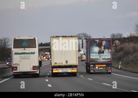 Elefantenrennen auf der dreispurigen AUTOBAHN A8 bei Augsburg. Ein Bus, Bus bei einem Überholmanöver auf der linken Spur - er überholt zwei LKWs. Verkehr, Autos, Autobahn, Autobahn. Weltweite Verwendung Stockfoto