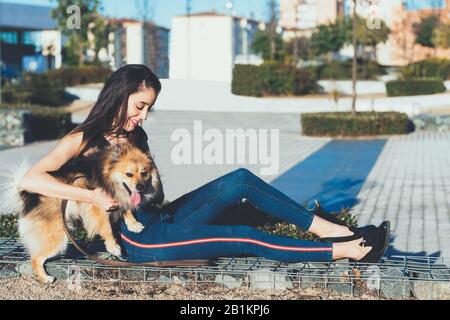 Attraktive junge Frau, die mit Hund in der Stadt sitzt Stockfoto