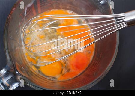 4 Eier mit einem Schneebesen schlagen Stockfoto