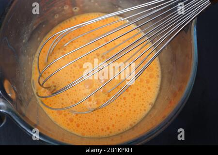 Eier mit einem Schneebesen schlagen Stockfoto