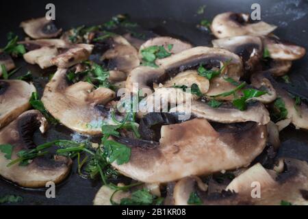 Pilze, die in einer Pfanne mit frischem Koriander braten Stockfoto