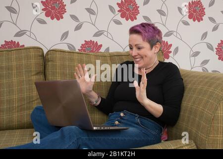 Eine Frau saß auf ihrem Sofa auf ihrem Laptop Stockfoto