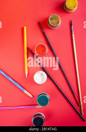 Farbbürsten und Farben auf rotem Hintergrund Stockfoto