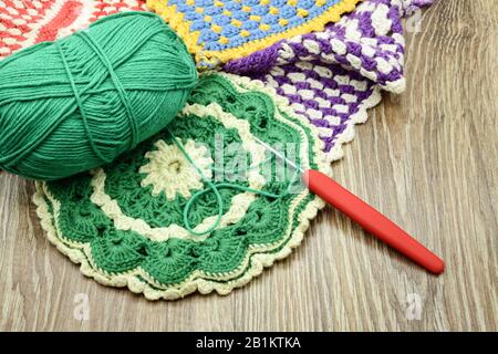 Traditionelle Häkel-Ofenhandschuhe aus grüner und beigefarbener Wolle. Nadelarbeit. Stockfoto