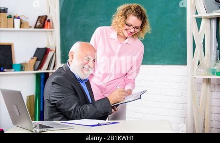Schüler, Lehrer über Aufgabe. Lösen von mathematischen Aufgaben. Schule Bildung Konzept. Hausaufgaben prüfen. Lehrer und Schüler auf der Suche nach Buch. Erklären schwieriges Thema. Studenten durch einige Informationen verwirrt. Stockfoto