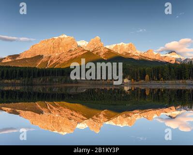 Sonnenaufgang auf dem Mount Rundle mit blauer Himmelsreflexion auf dem Rundle Forebay Reservoir im Herbst in Canmore, Kanada Stockfoto