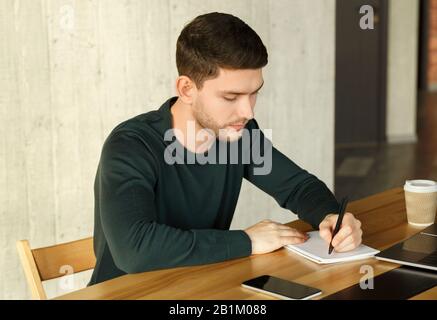 Junger Mitarbeiter, Der Im Modernen Büro Sitzt Stockfoto